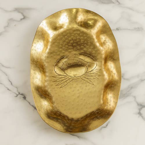 Gold decorative plate with a crab design on a marble surface