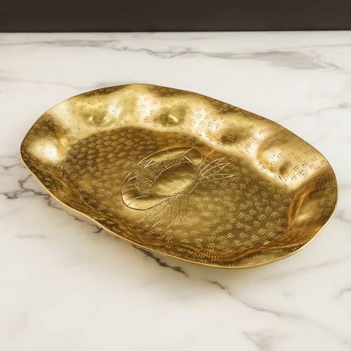 Gold decorative plate with engraved crab design on a marble surface