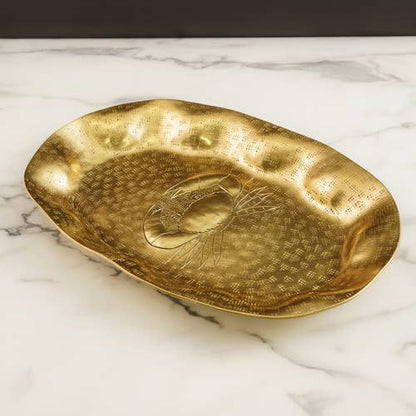 Gold decorative plate with engraved crab design on a marble surface