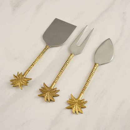 Set of three silver cutlery pieces with gold leaf designs on a white background
