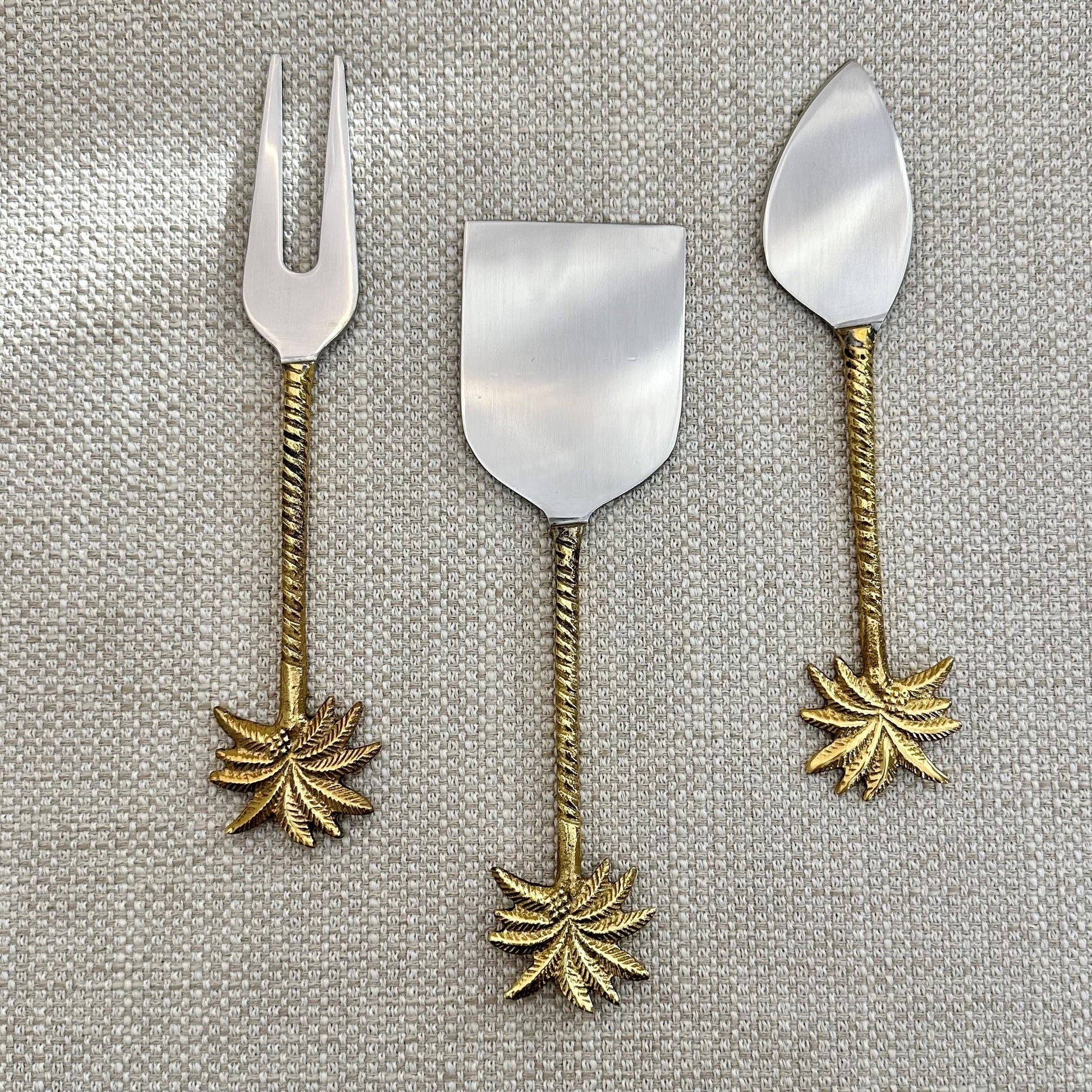 Set of three metal dessert spoons with leaf designs on a textured gray background