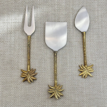 Set of three metal dessert spoons with leaf designs on a textured gray background