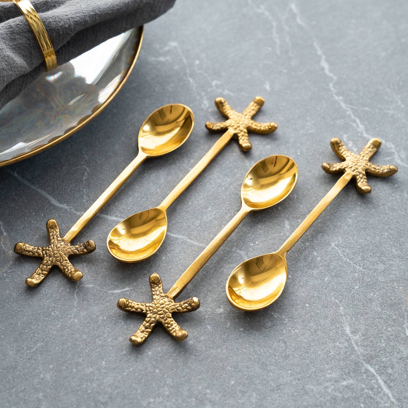 Set of gold spoons with starfish ends on a gray surface
