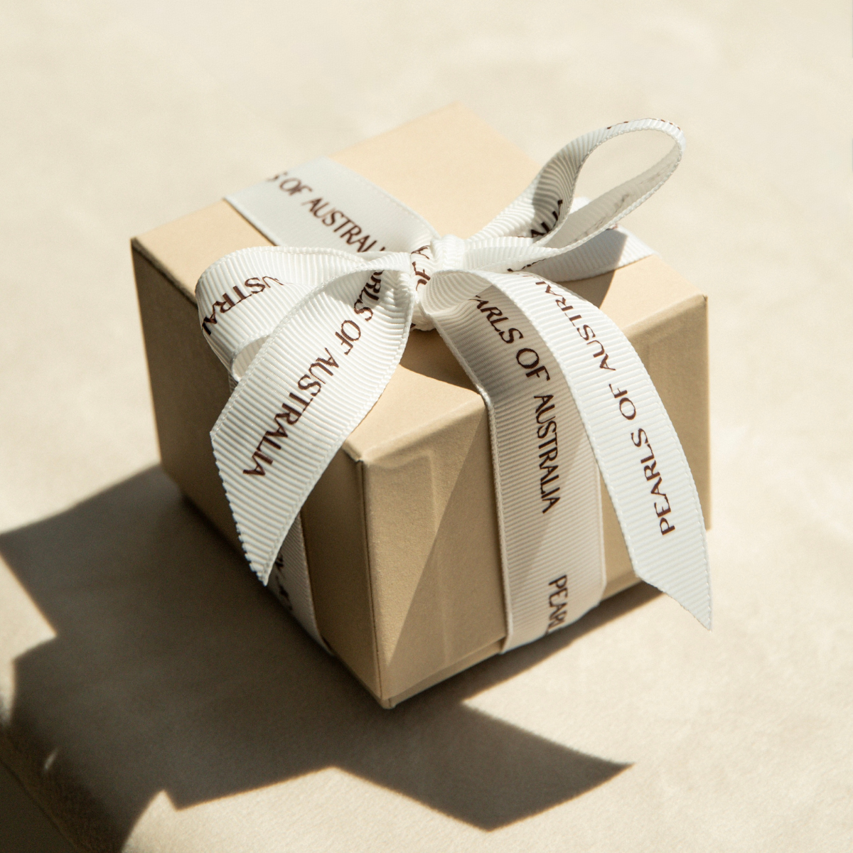 Pearls of Australia gift box wrapped with a ribbon on a beige background