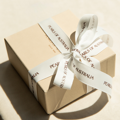 Gift box with a white ribbon and 'Pearls of Australia' branding on a beige background