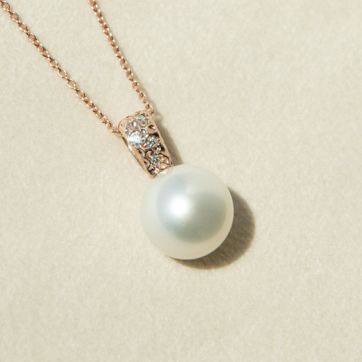 Pearl necklace with rose gold chain on a beige background
