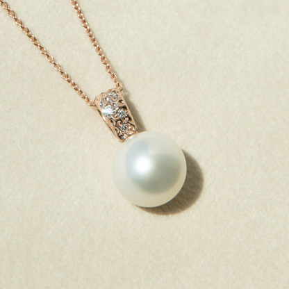 Pearl necklace with rose gold chain on a beige background