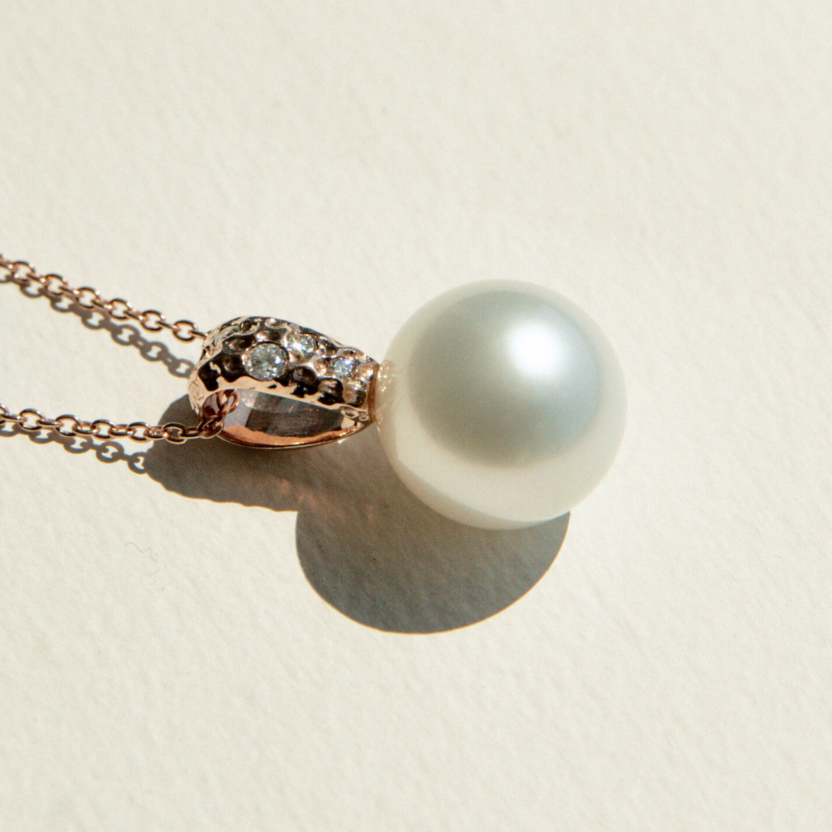 Pearl necklace with rose gold clasp on a beige background
