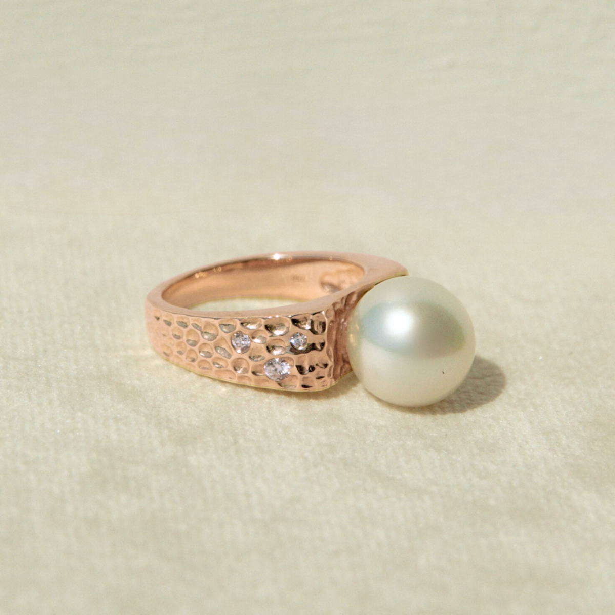 Rose gold ring with a pearl on a beige background