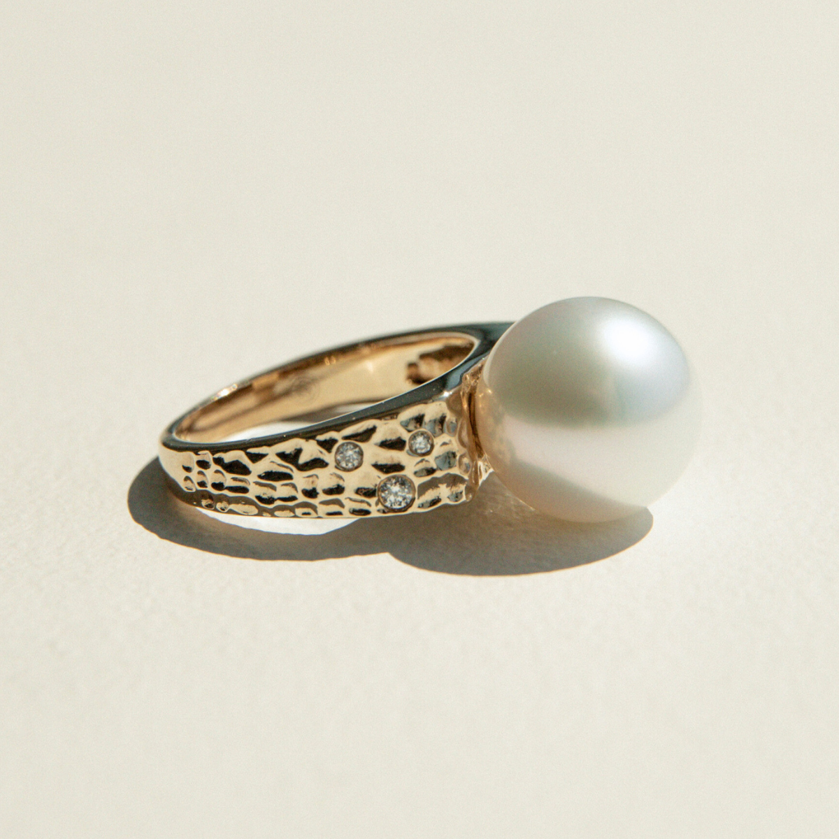 Gold ring with a pearl on a beige background
