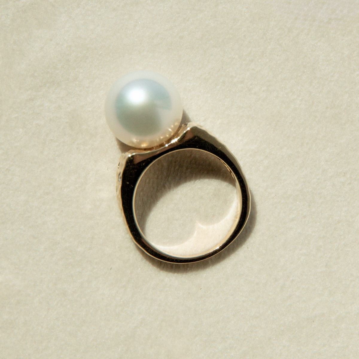 Pearl ring on a textured beige background
