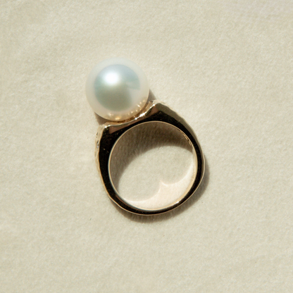Pearl ring on a textured beige background