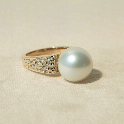 Gold ring with a large pearl on a beige background