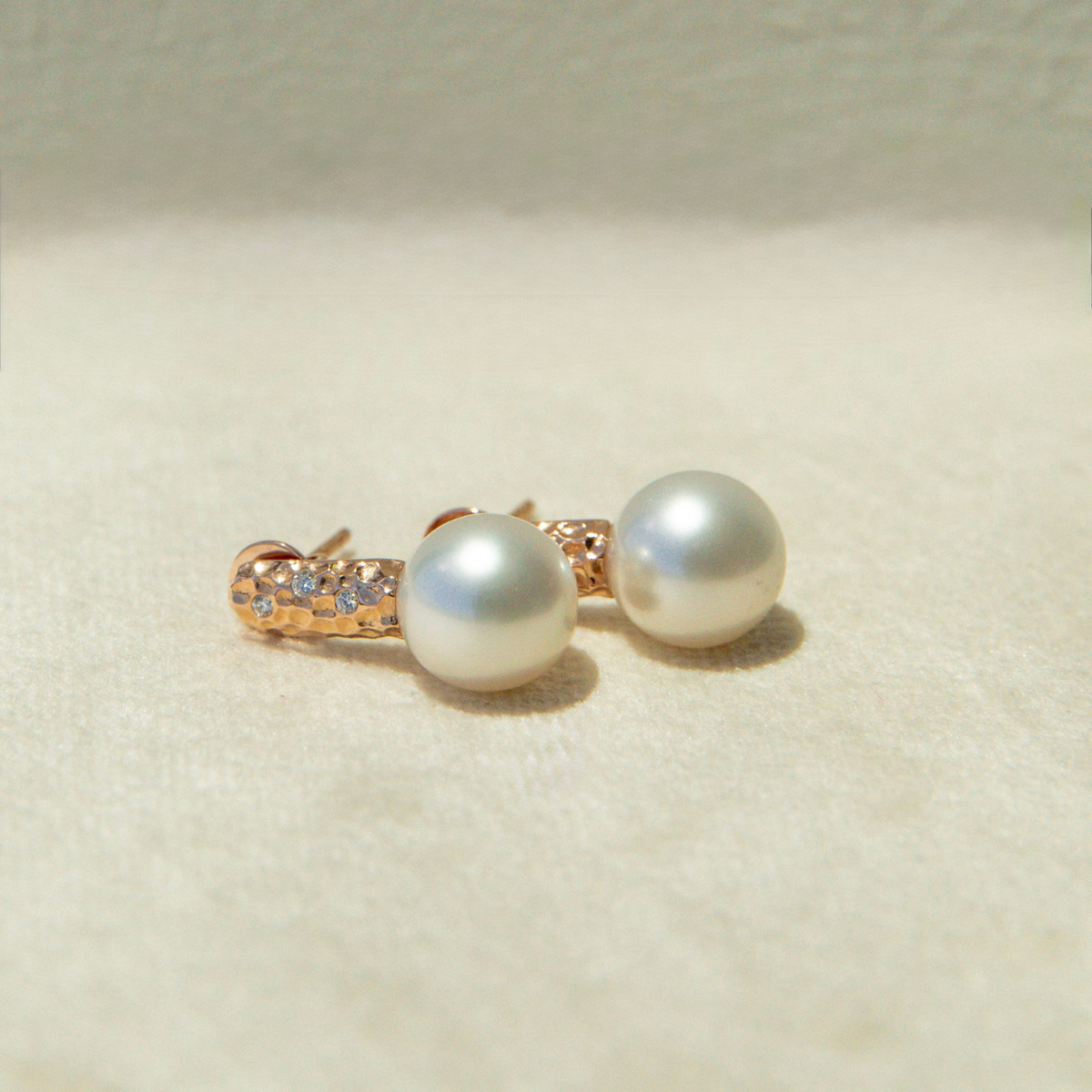 Pair of pearl earrings with gold accents on a light beige background