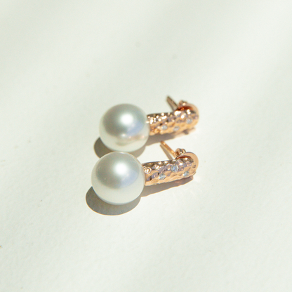 Pearl earrings with rose gold clasps on a light background
