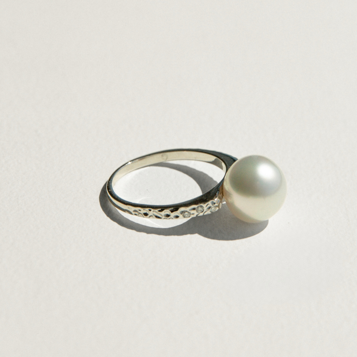 Pearl ring with white gold band on a light gray background