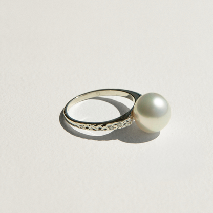 Pearl ring with white gold band on a light gray background