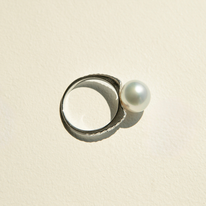 White gold ring with a pearl on a beige background