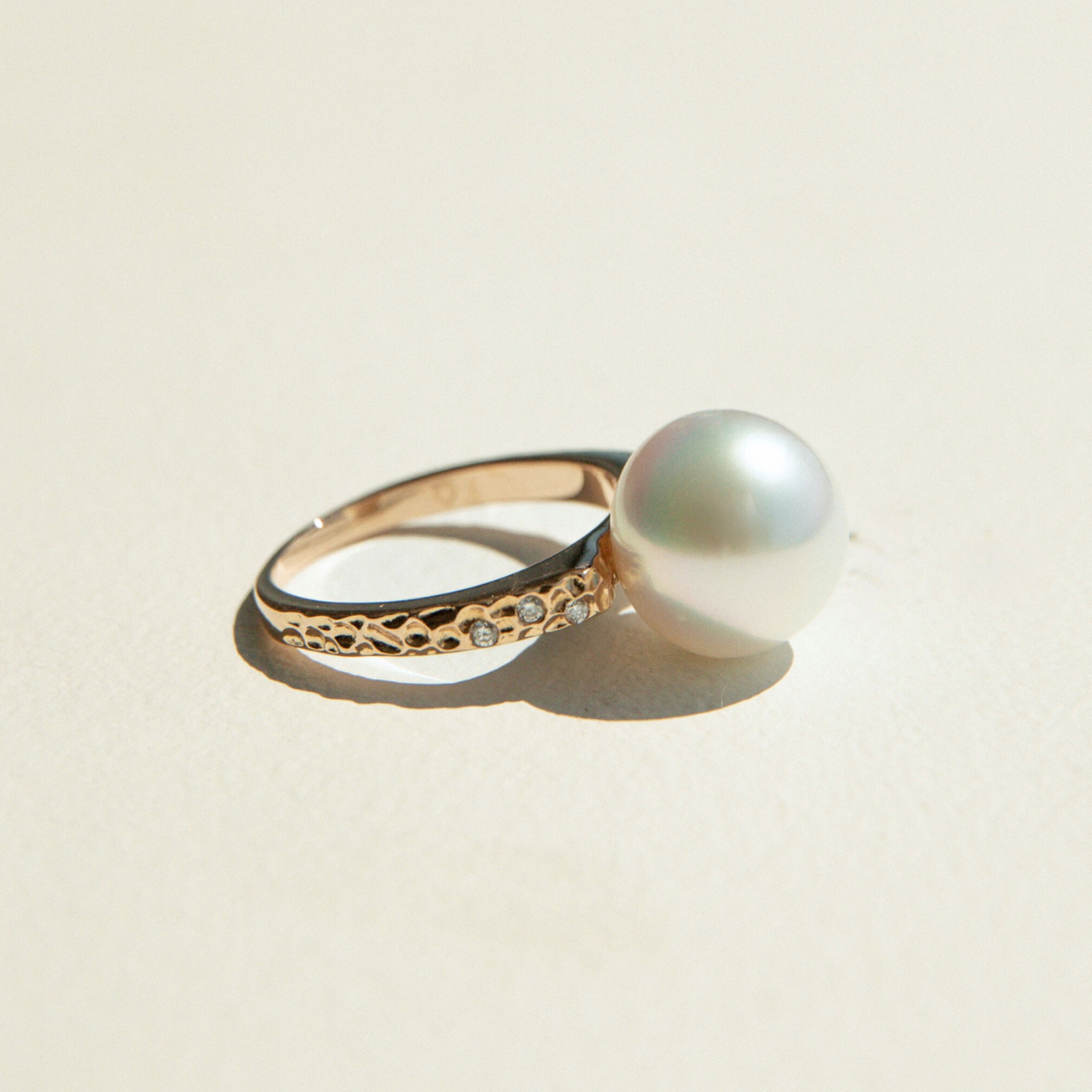 Gold ring with a pearl on a beige background
