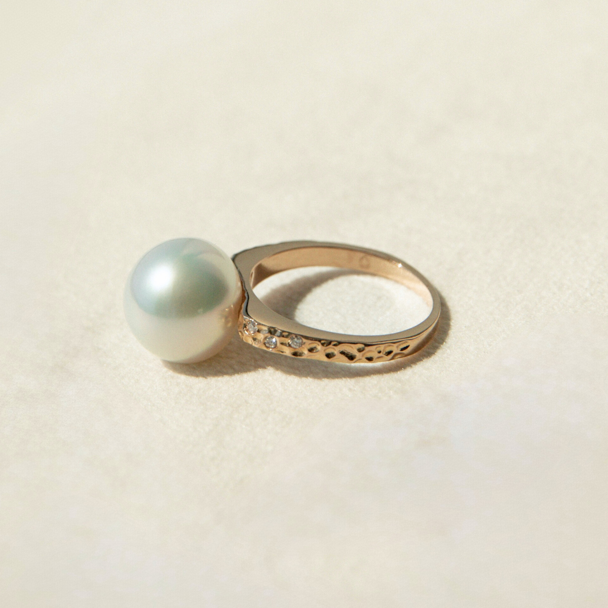 Gold ring with a large pearl on a beige background