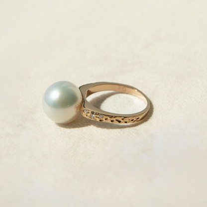 Gold ring with a large pearl on a beige background