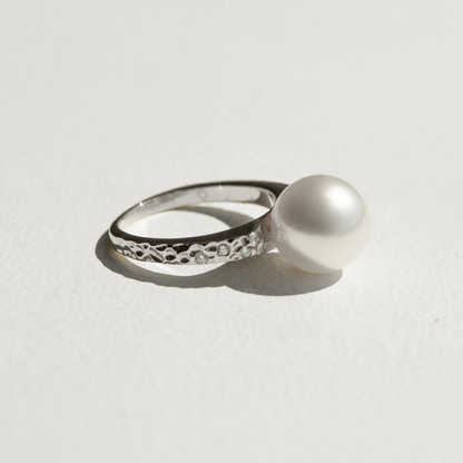White gold ring with a pearl on a light gray background