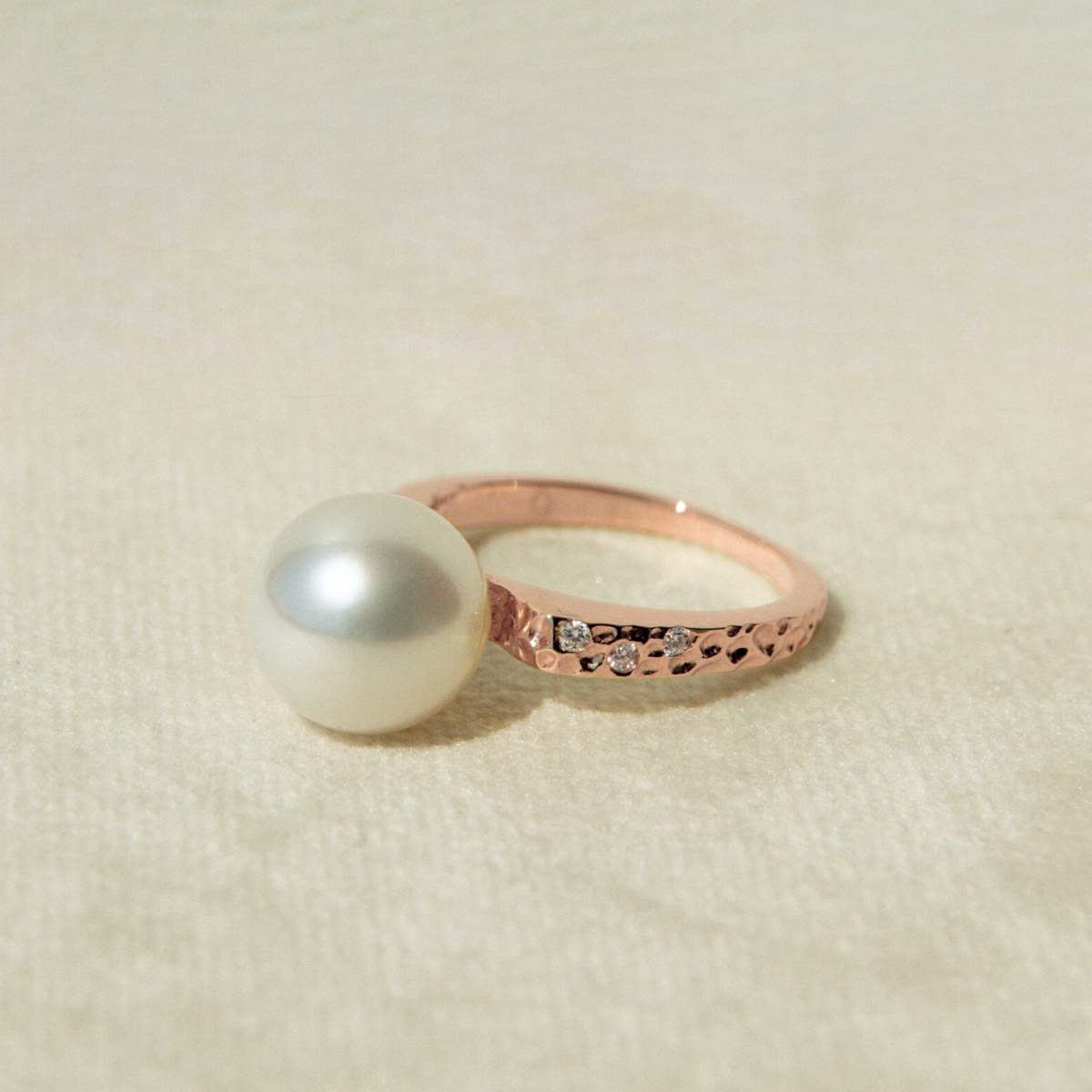 Rose gold ring with a pearl on a beige background