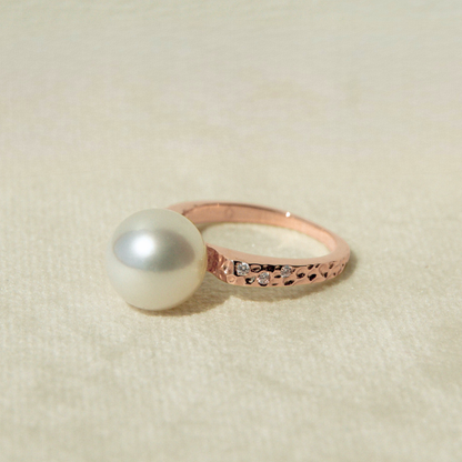 Rose gold ring with a pearl on a beige background