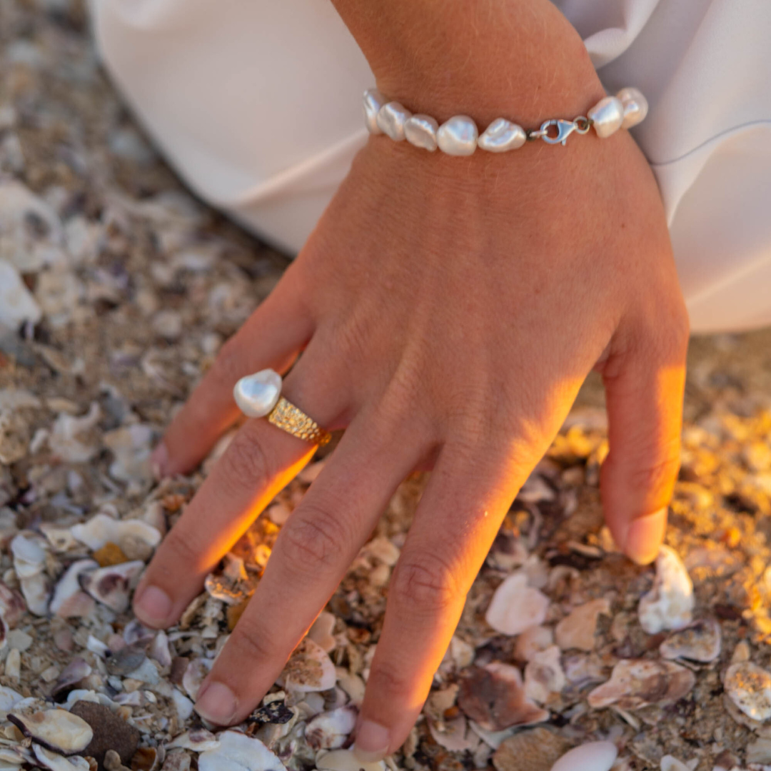 A woman wears her beautiful Impressions Pearl Keshi Ring set in a hammered gold design.