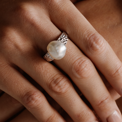 A woman wears her beautiful Impressions Pearl Keshi Ring set in a hammered gold design.