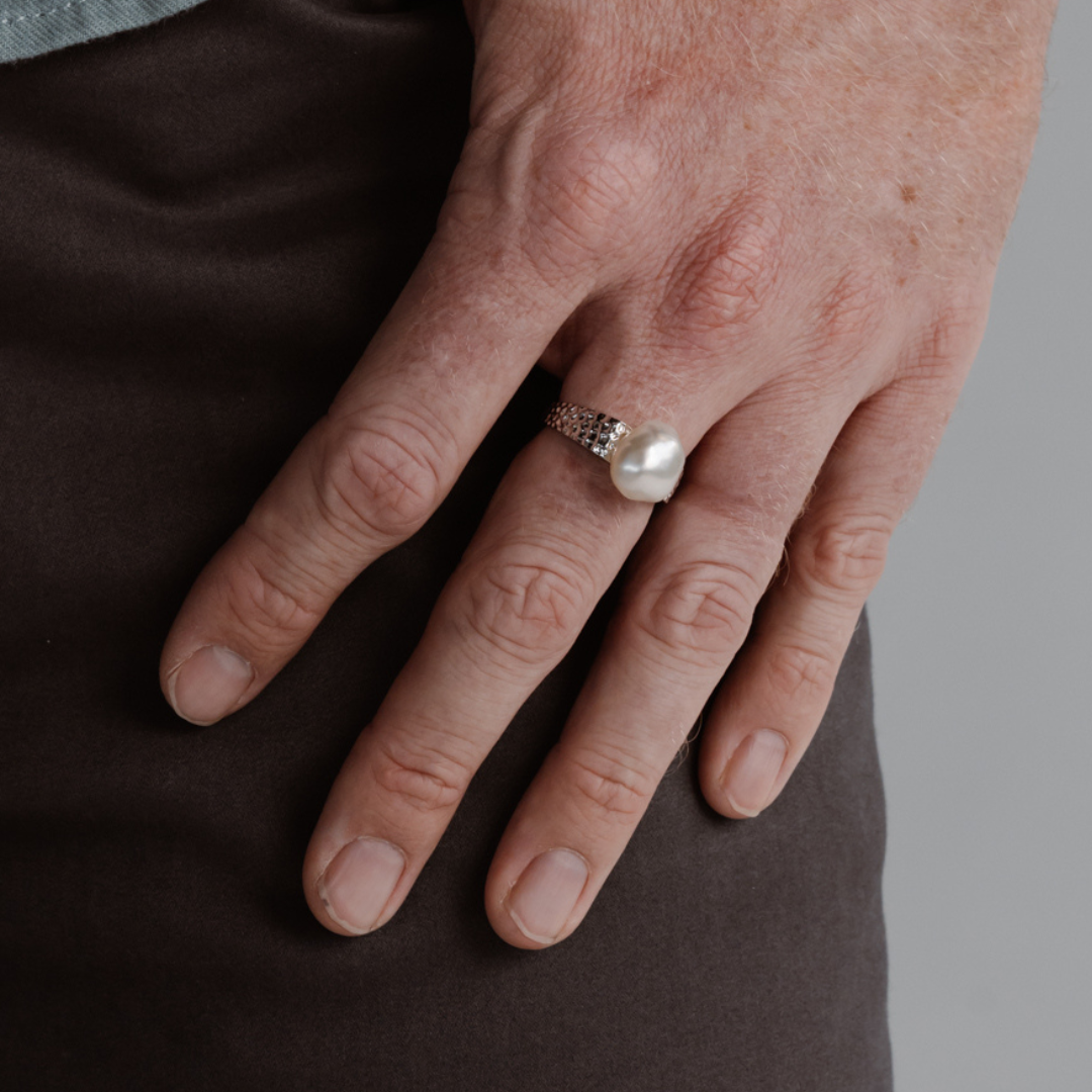 A man wears his beautiful Impressions Pearl Keshi Ring set in a hammered gold design.