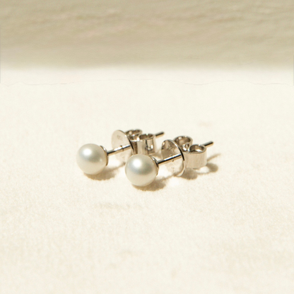 Pair of keshi pearl stud earrings on a beige background