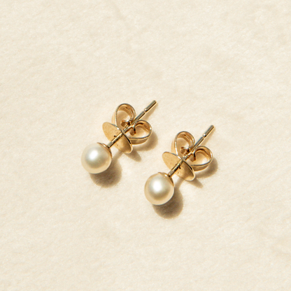 Pair of keshi pearl earrings on a beige background