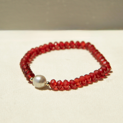 Red beaded bracelet with a pearl on a beige background