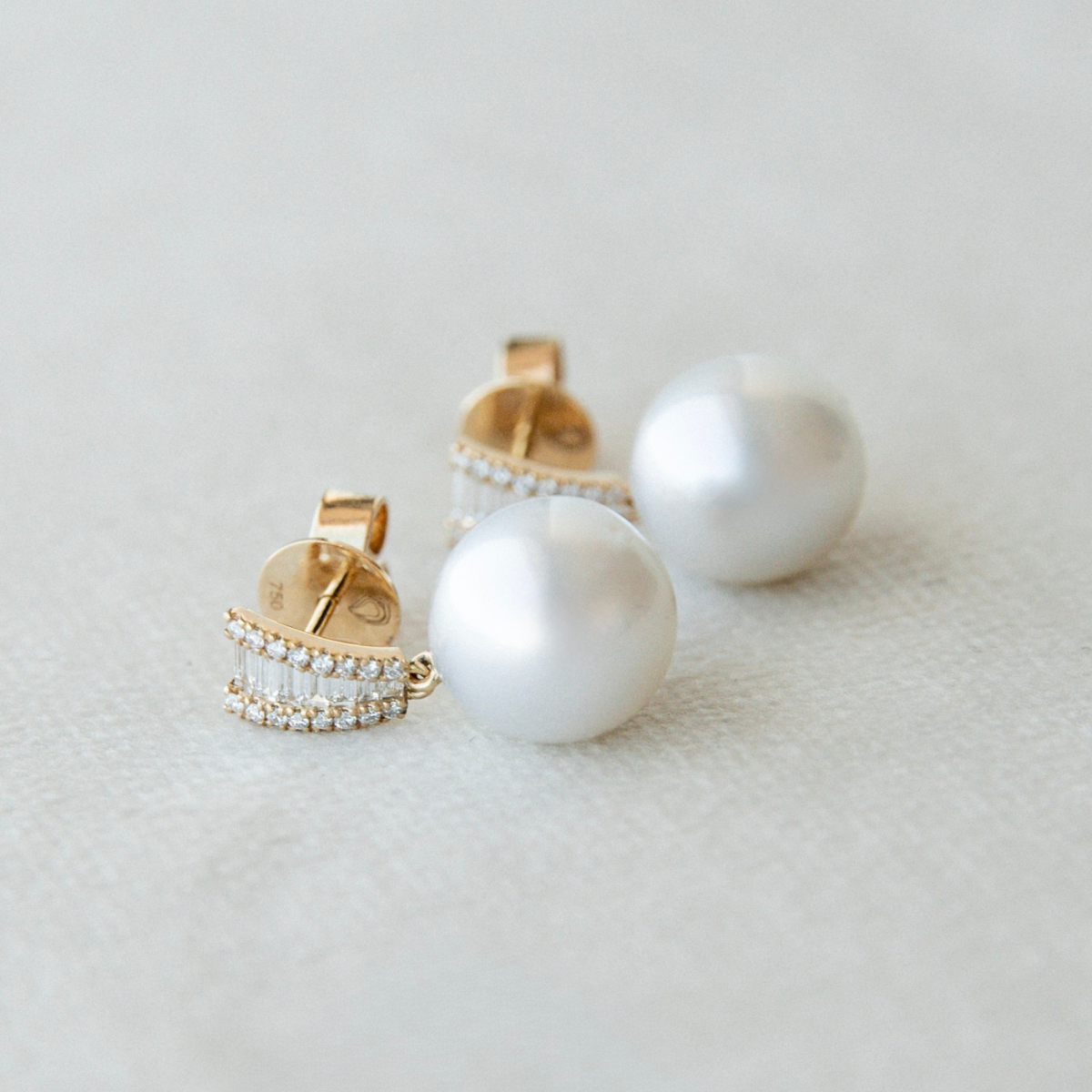 Pearl earrings with gold and diamond accents on a light background