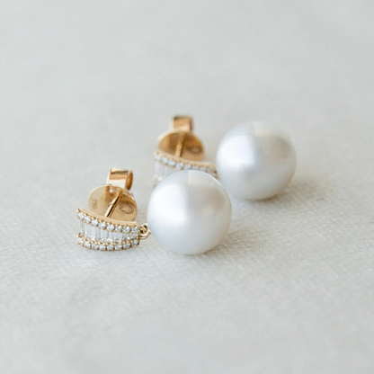 Pearl earrings with gold and diamond accents on a light background