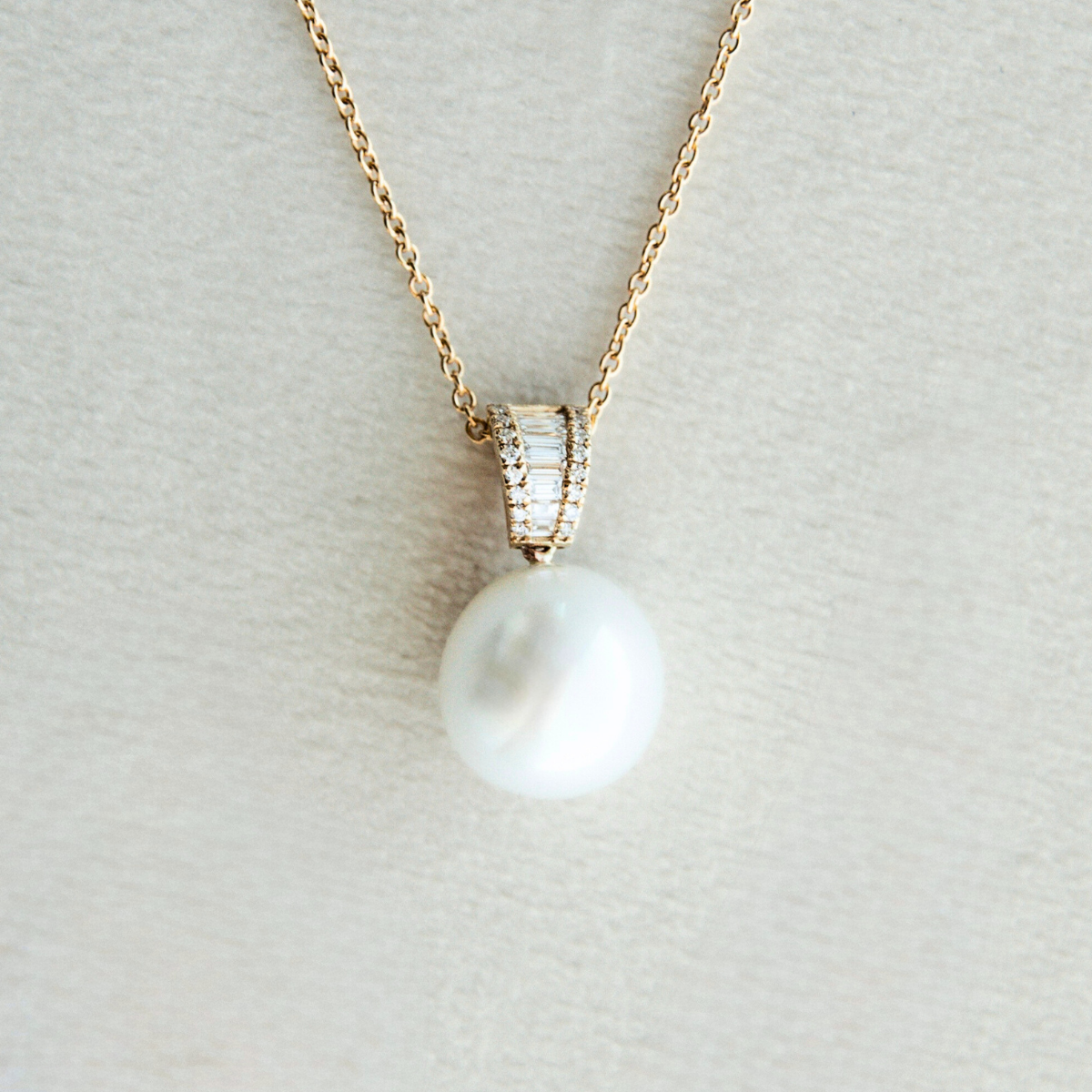 Pearl necklace with gold chain on a light gray background