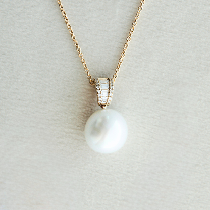 Pearl necklace with gold chain on a light gray background