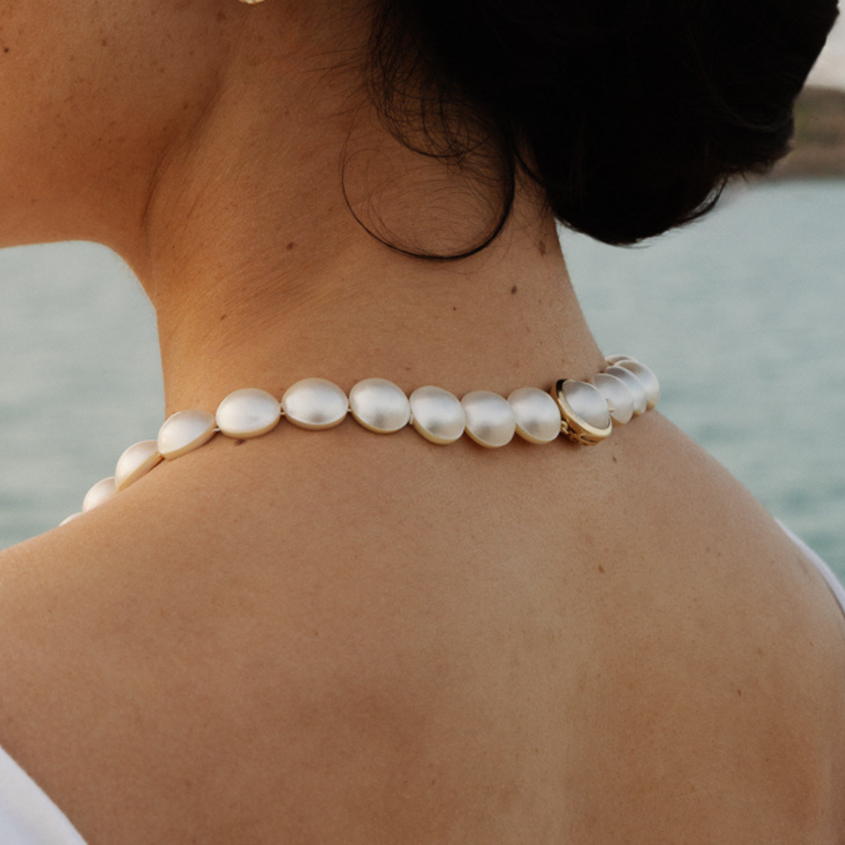 Mabe pearl strand necklace worn by a person with a blurred background