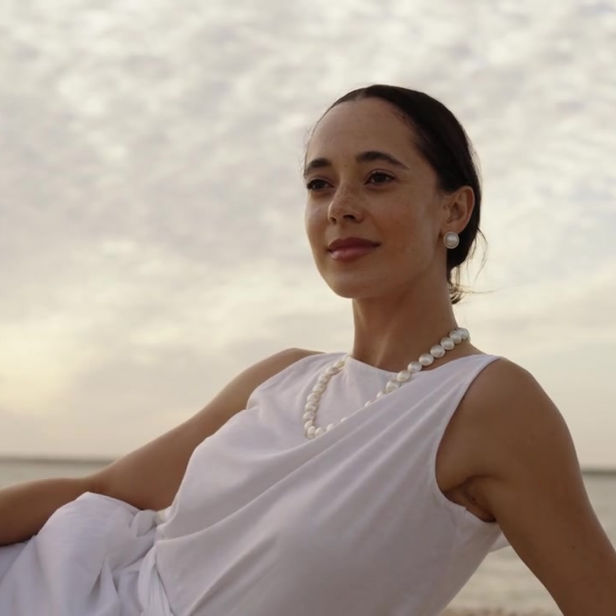 A woman wears her stunning Mabe Pearl Strand Necklace and Rope Mabe Pearl Studs while laying at our Cygnet Bay Pearl Farm's Shell Island.
