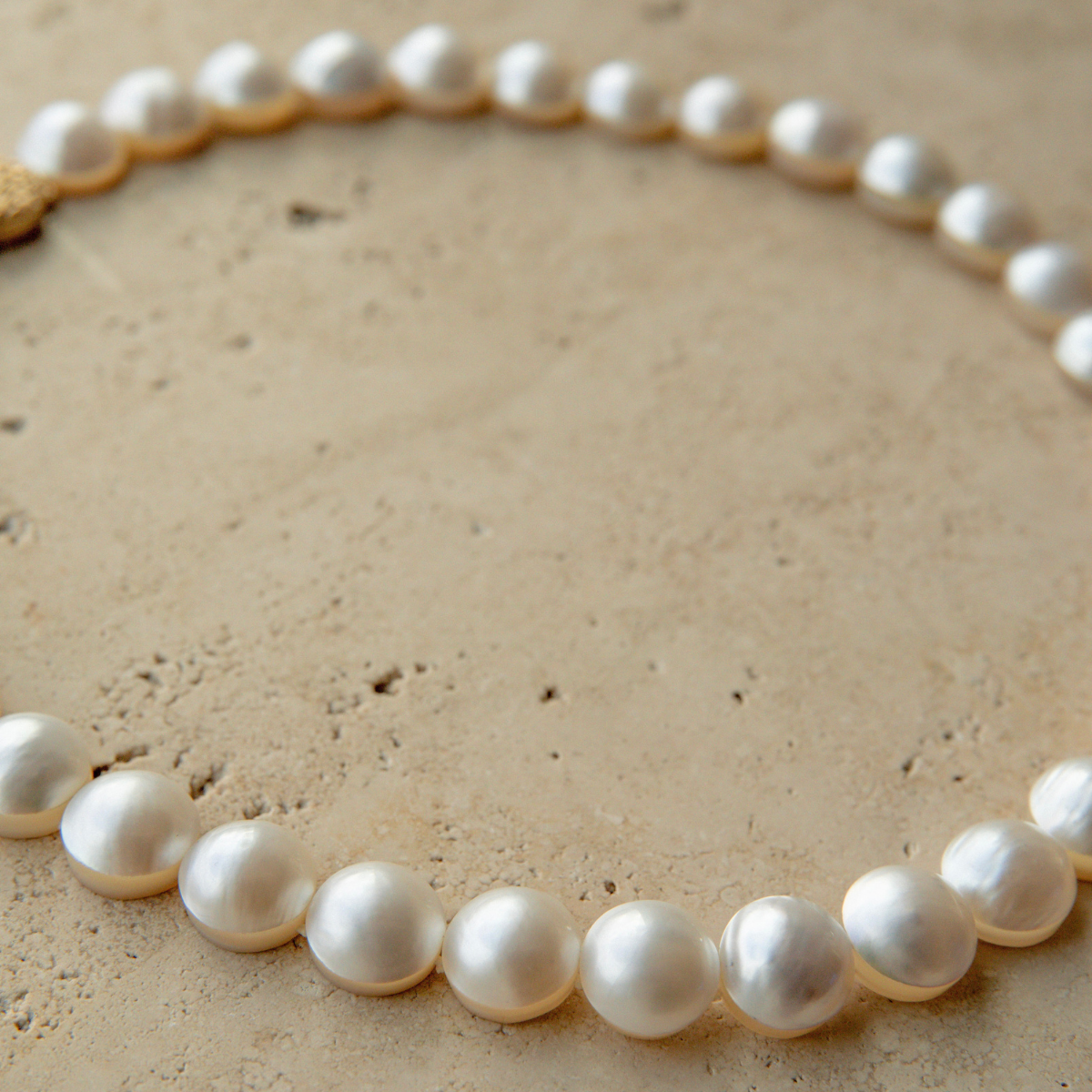Mabe pearl strand necklace on a textured beige surface
