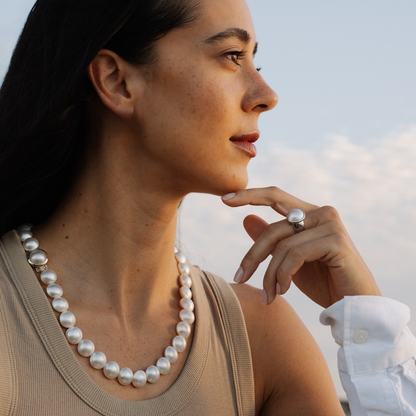 Woman wearing a mabe pearl strand necklace with a blurred background