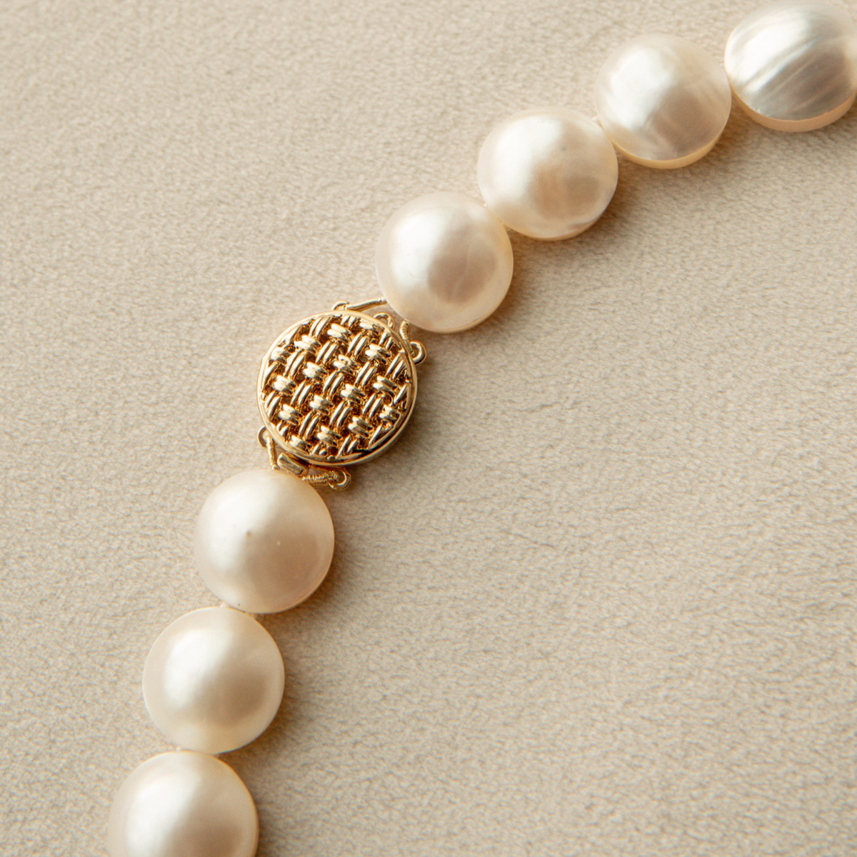 Mabe pearl strand necklace with a gold clasp on a beige background
