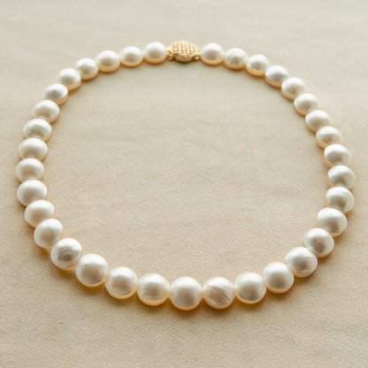 Mabe pearl strand necklace with a gold clasp on a beige background