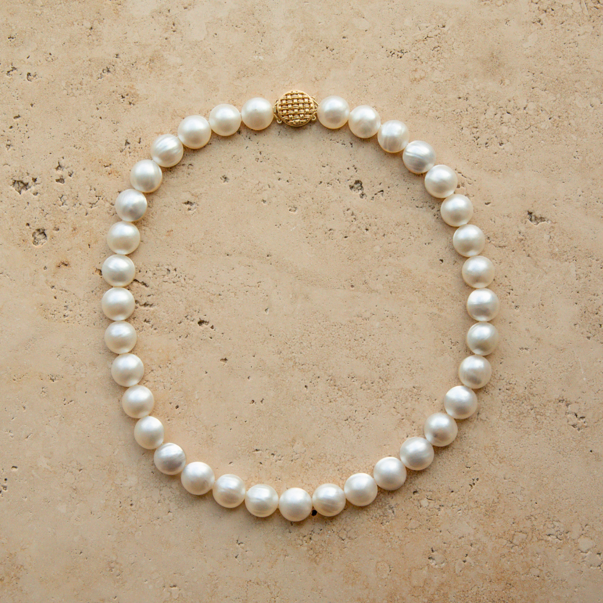 Mabe pearl strand necklace with a gold clasp on a beige surface