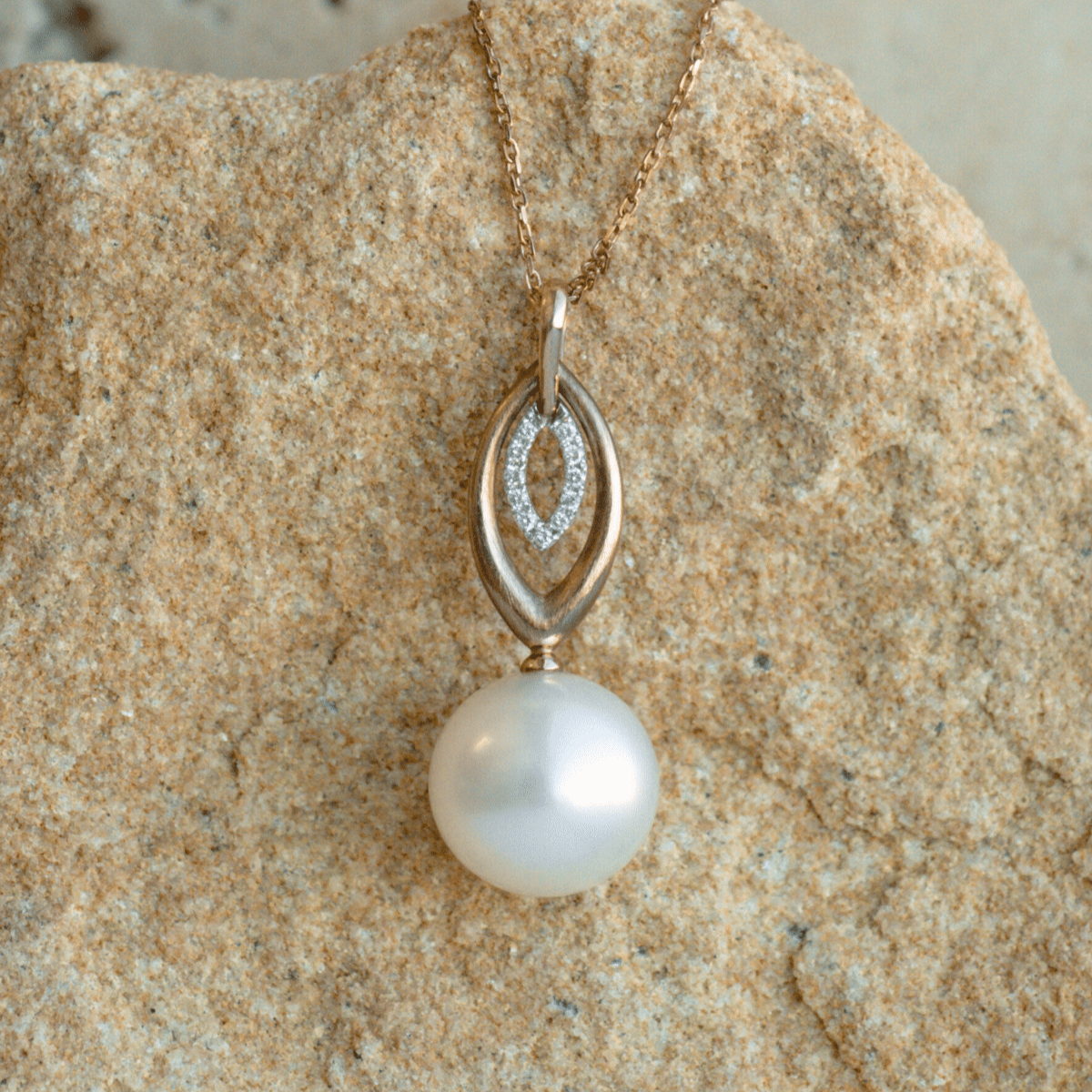 A unique Marquise Pearl Pendant featuring a round Australian South Sea pearl set alongside a marquise shaped diamond halo and gold design.