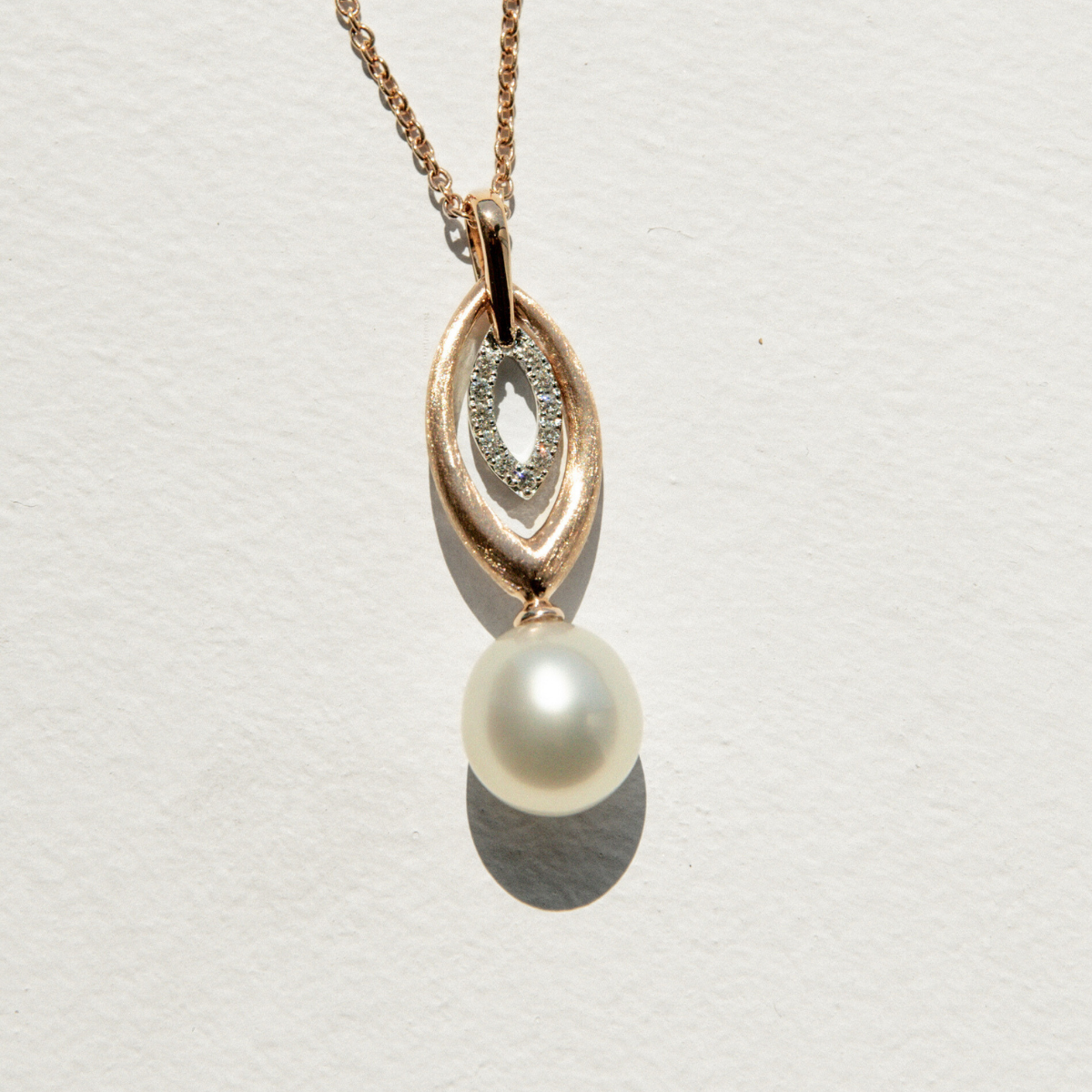 Pearl pendant on a chain against a light gray background