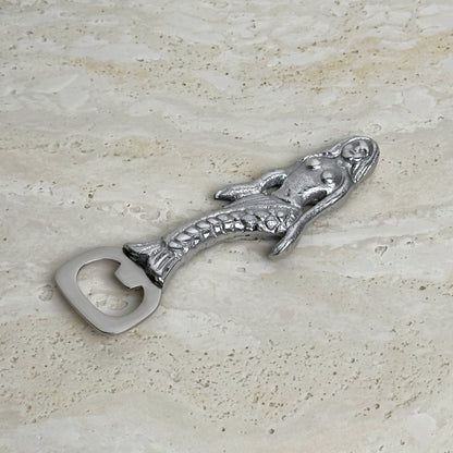 Metallic mermaid bottle opener on a textured surface
