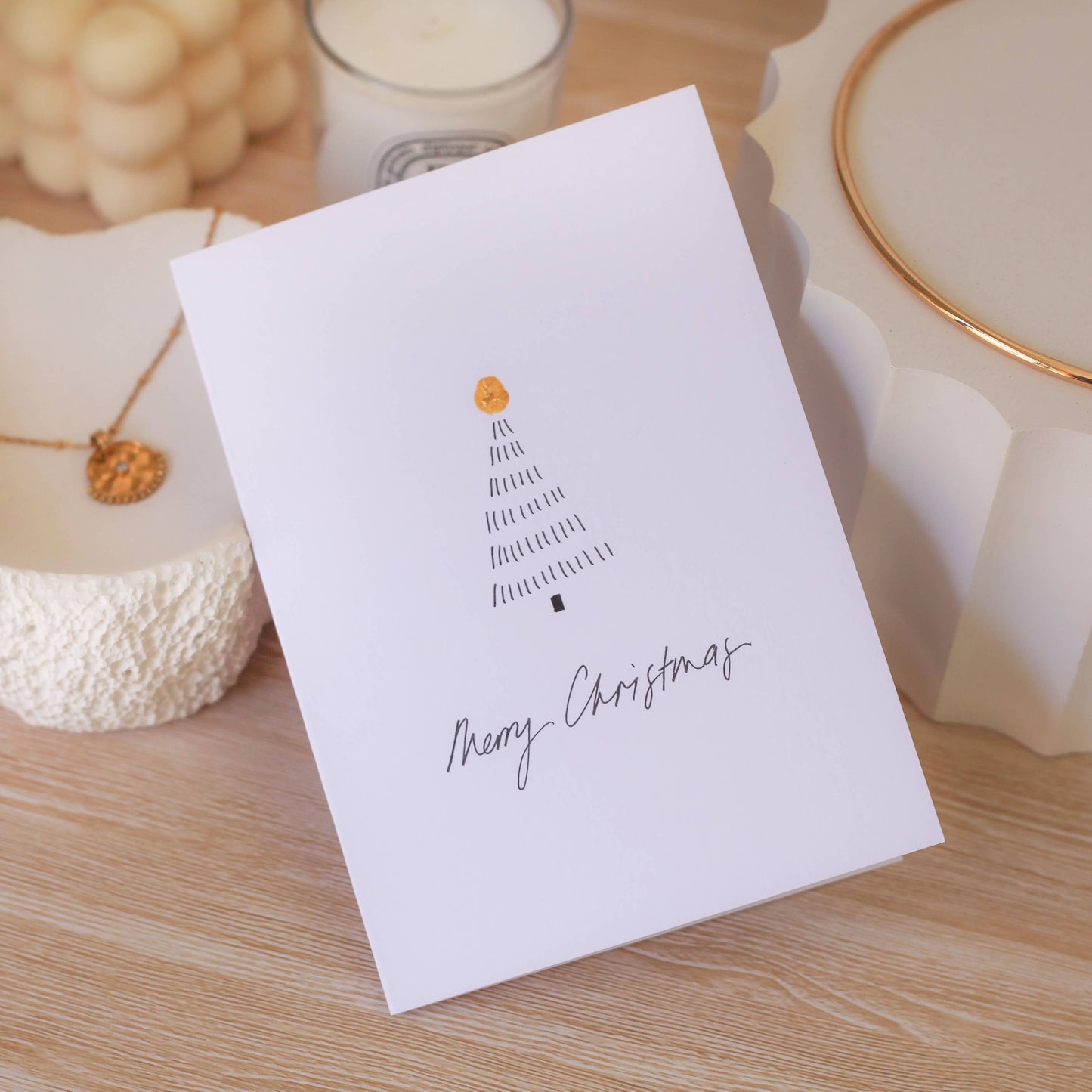 White card with Christmas tree design and 'Merry Christmas' text on a wooden surface.