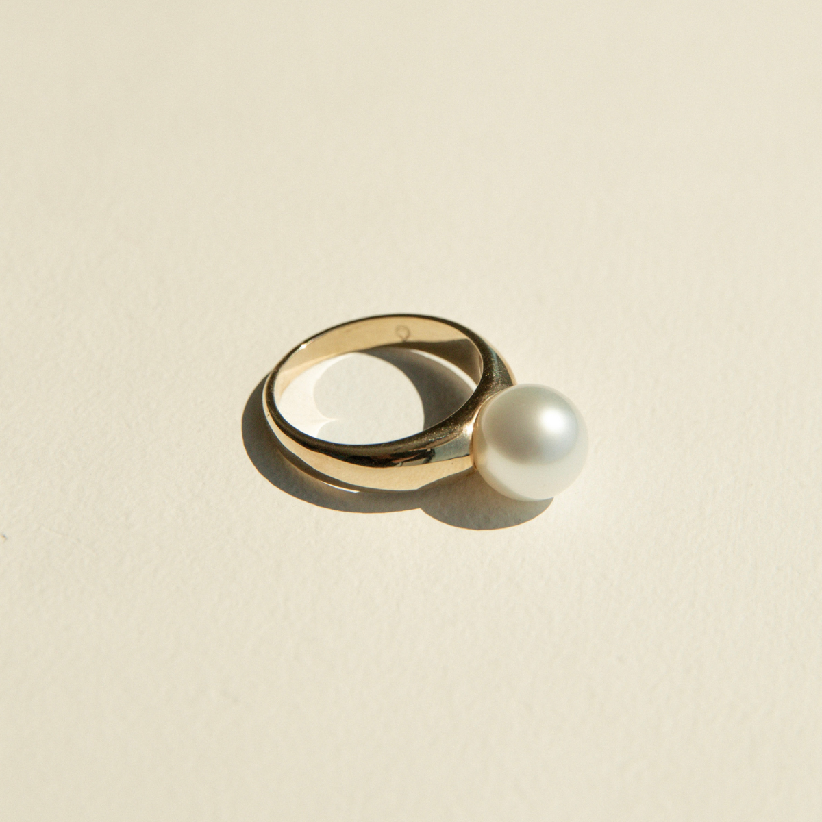 Gold ring with a pearl on a beige background